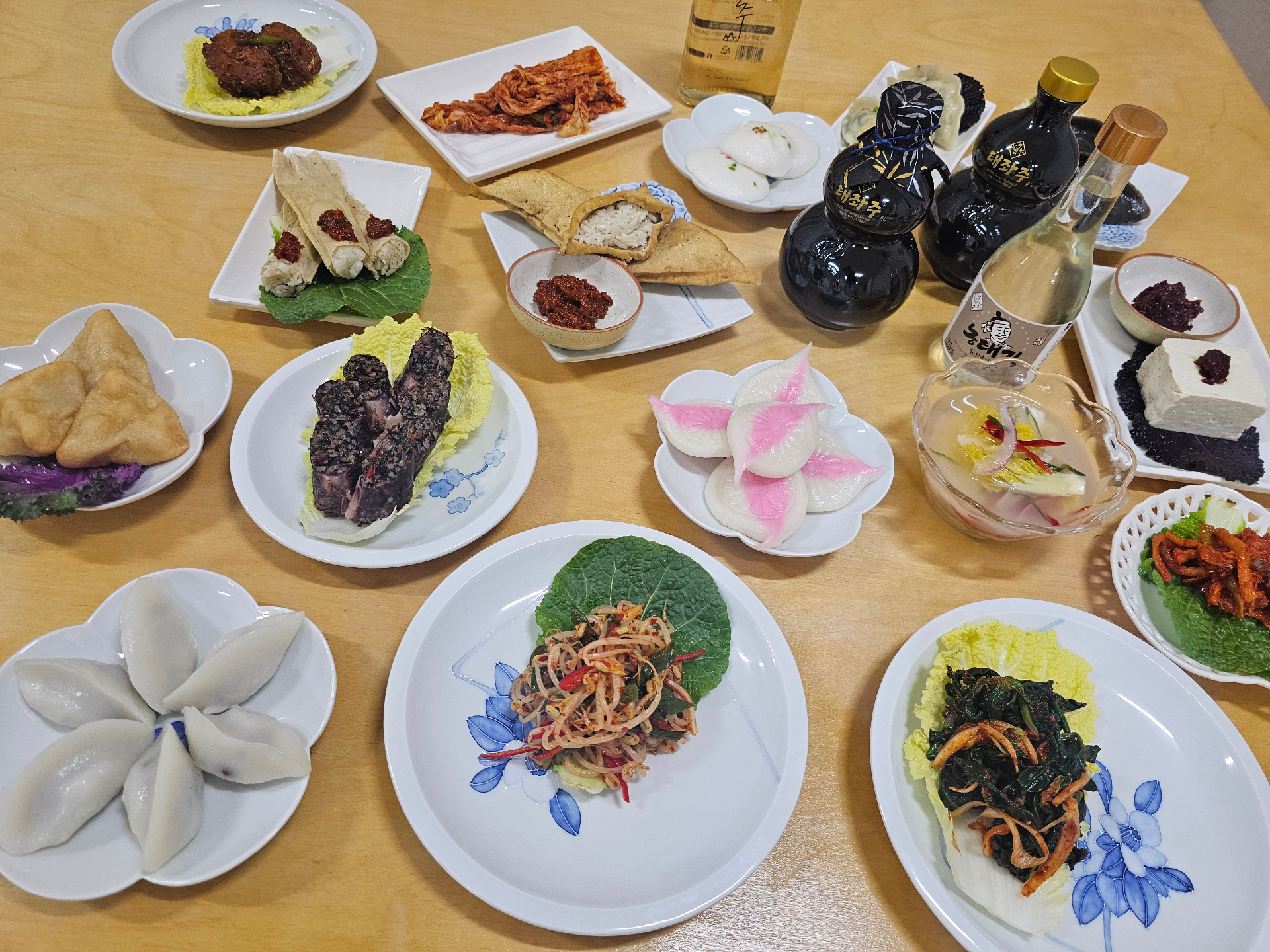 Elaborate Korean feast spread with multiple traditional dishes and premium sool bottles for authentic dining experience